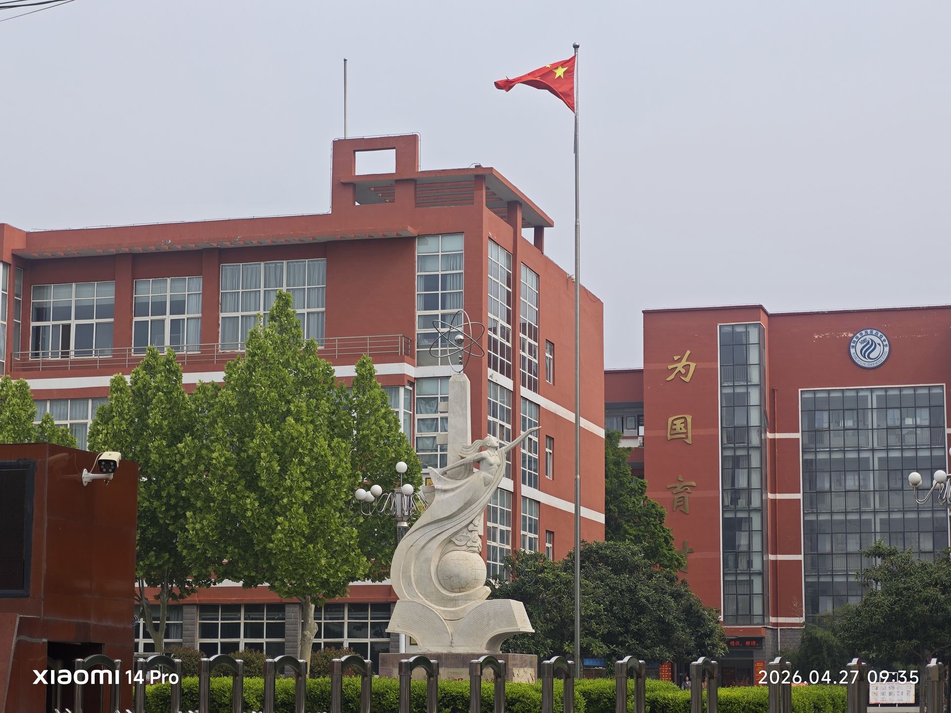 校园内红色教学楼巍然矗立，楼顶五星红旗迎风飘扬，青春的活力在砖瓦间流淌。